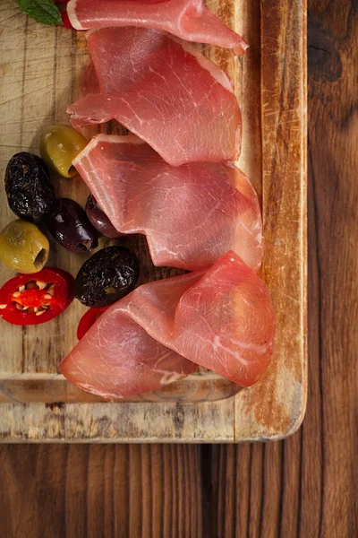 Piatto di carne di Carne stagionata e olive su vecchia tavola di legno — Foto Stock