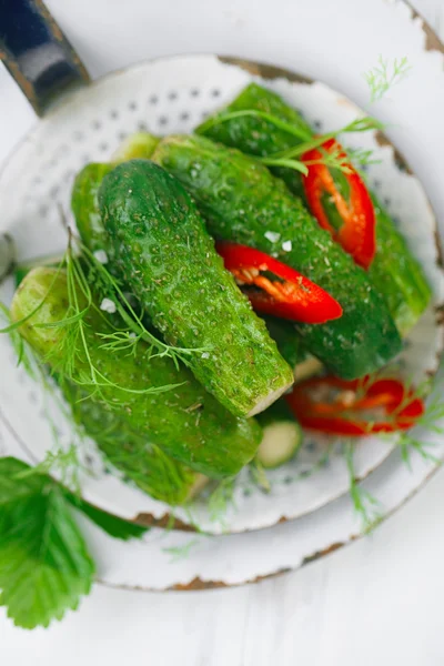 Freshly-salted cucumbers on vintage enamel sieve — Stock Photo, Image