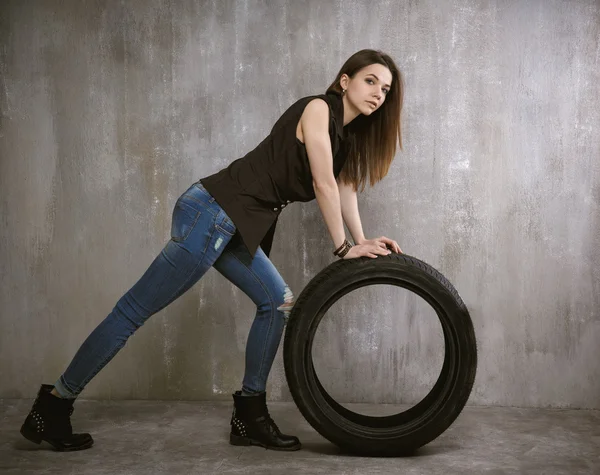 Joven, chica sexy, ruedas de neumáticos de coche en el fondo de cono gris — Foto de Stock