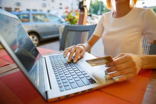 Chica con un ordenador portátil en un café, tienda con una tarjeta de crédito — Foto de Stock