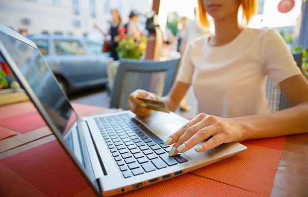 Menina com um laptop em um café, loja com cartão de crédito — Fotografia de Stock