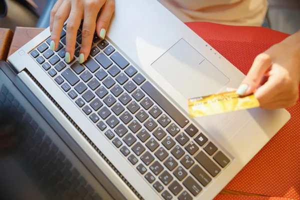 Chica con un ordenador portátil en un café, tienda con una tarjeta de crédito — Foto de Stock