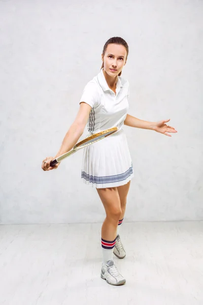 Menina bonita em roupas de tênis, brandindo uma raquete de tênis em — Fotografia de Stock