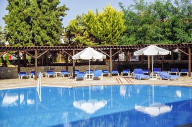 büyük yüzme havuzu güneş şezlong ve şemsiye ile