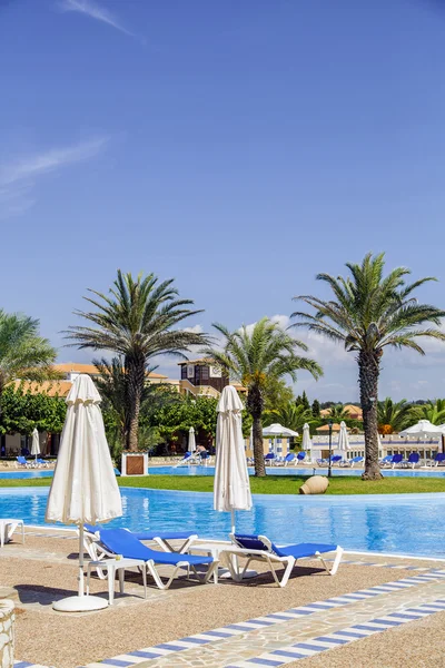 Swimming pool with sun loungers, parasols and palm trees — Stock Photo, Image