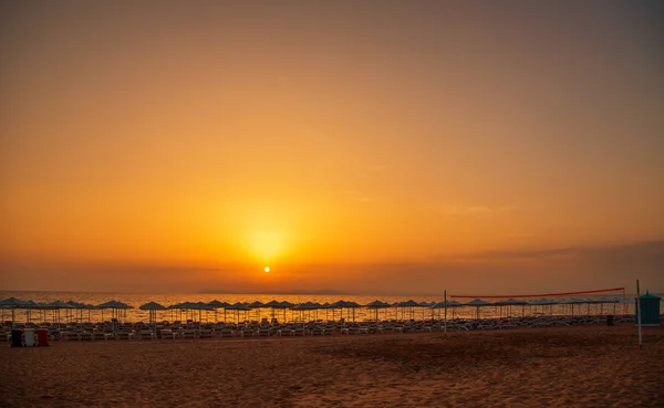 Ηλιοβασίλεμα στην παραλία με ξαπλώστρες, ομπρέλες και volley θάλασσα — Φωτογραφία Αρχείου