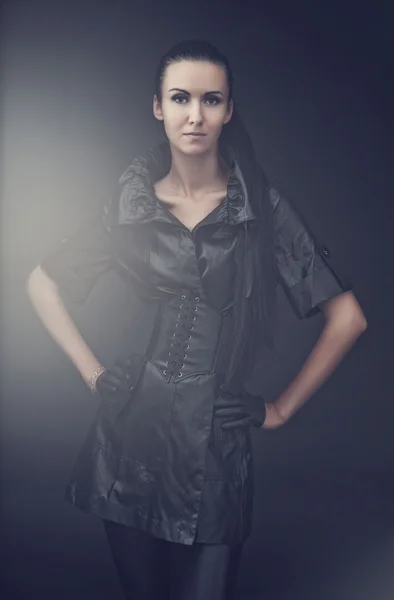 Mulher em um casaco de couro e luvas pretas em um fundo preto — Fotografia de Stock