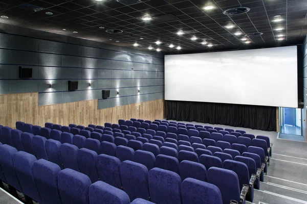 用大量的座位和一个大屏幕室内电影院大厅 — 图库照片