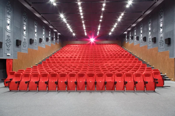 Teatro interior com cadeiras vermelhas e projetor luminoso . — Fotografia de Stock