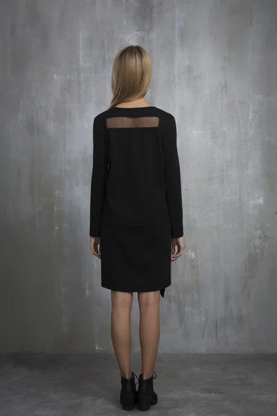Menina na moda em vestido preto em pé sobre um fundo cinza, t — Fotografia de Stock