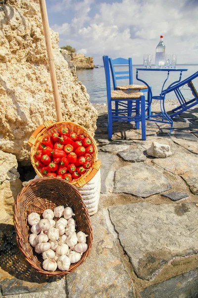 Basket with pepper and garlic on a background of sea and rocks. — Stock Photo, Image
