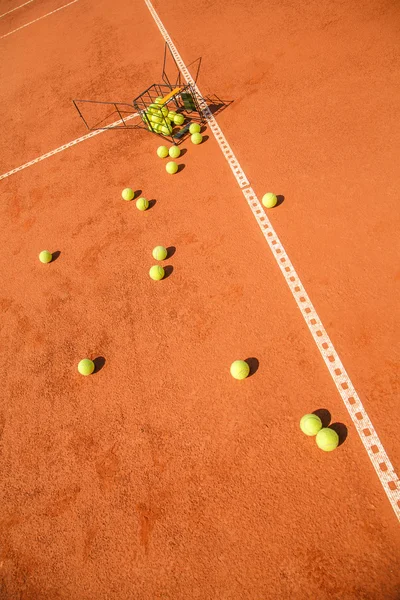 Basket of tennis balls scattered around the court Stock Picture