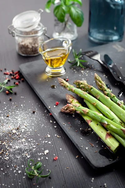 Färsk sparris med olivolja och kryddor på mörk bakgrund — Stockfoto