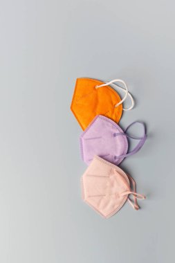 Three colorful FFP face masks on grey background, top view