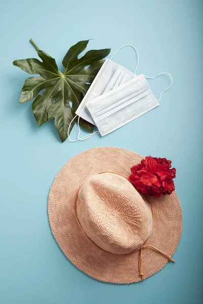 Sombrero de paja con flor tropical sobre azul, sombras de hojas de palma. Configuración de vista superior Flatlay imitando el día de playa soleado Imagen de archivo