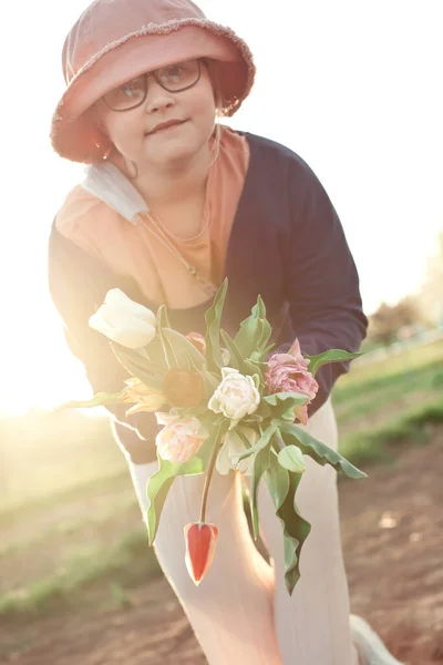 Un tas de tulipes pour vous : jeune adolescente portant des lunettes et un chapeau tenant un tas de tulipes — Photo