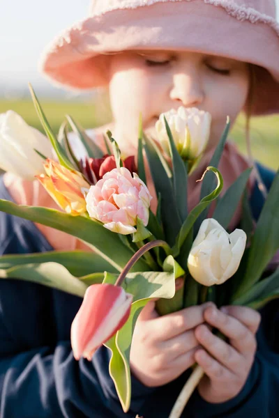 Retrato de cerca de una joven preadolescente feliz sosteniendo un ramo de tulipanes y oliendo las flores — Foto de Stock