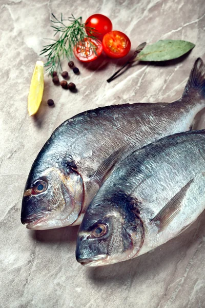 Two sea breams with tomatoes and herbs on kitchen table — Stock Image Two sea breams with tomatoes and herbs on kitchen table Royalty Free Stock Photos