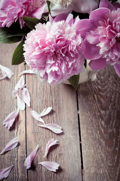 Peonie rosa con petali caduti sul tavolo di legno, primo piano — Foto Stock