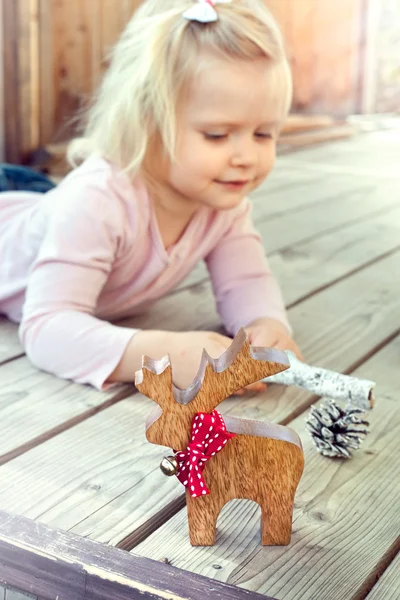 Bambina che gioca con le decorazioni natalizie renne e co — Foto Stock