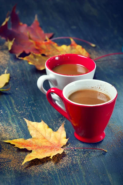 Due tazze di caffè con foglie autunnali, su fondo di legno — Foto Stock