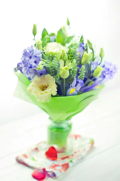 Bunch of flowers in a vase set with two red glass hearts — Stock Photo, Image