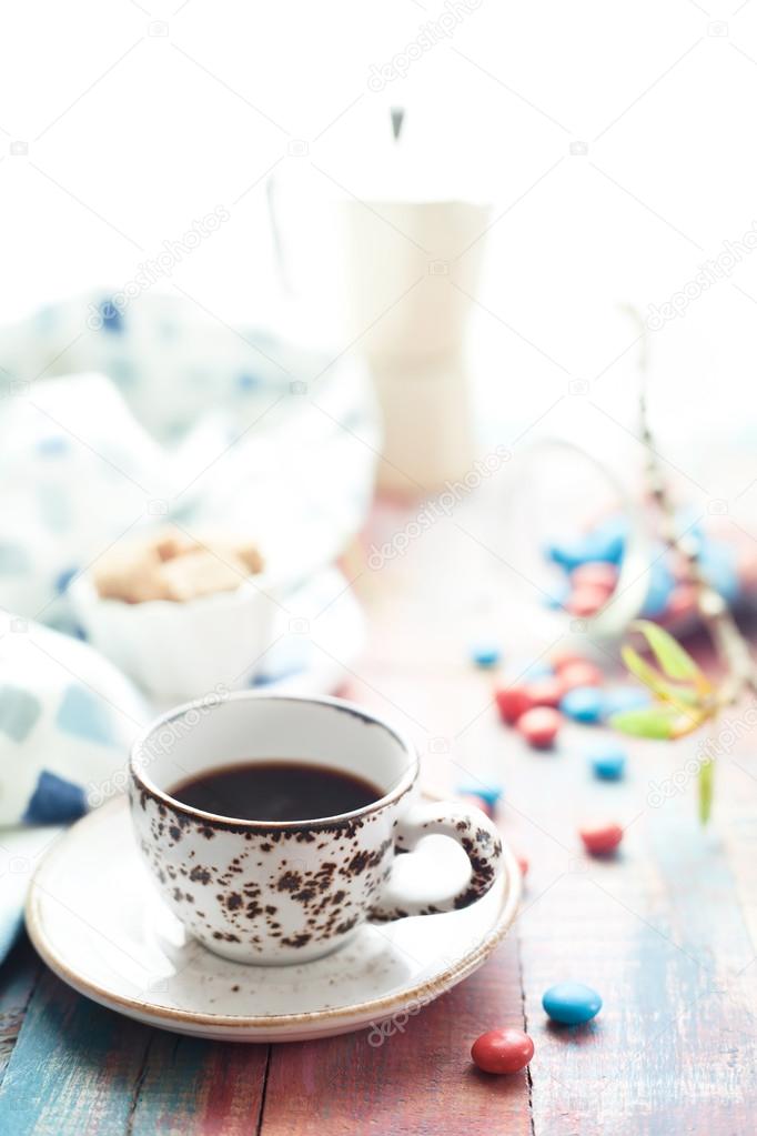 Cup of espresso with colorful sweets on wooden table