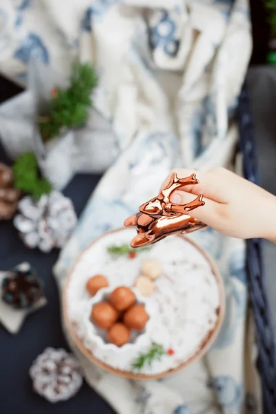 Childs mano mettendo una statuetta renna sulla tavola del pranzo di Natale — Foto Stock