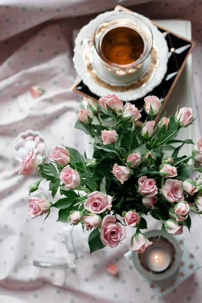 Bucn of pink roses set with a cup of tea and candles. — Stock Photo, Image