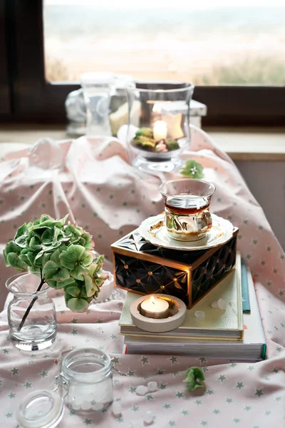 Secangkir teh dalam pengaturan kamar romantis dengan lilin dan bunga — Stok Foto