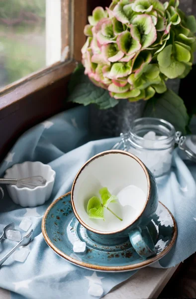 Empty cup on the attic window set with flowers — Stock Photo, Image