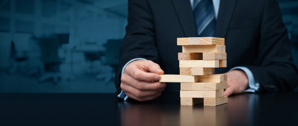 Бизнесмен снимает одну деталь с башни
