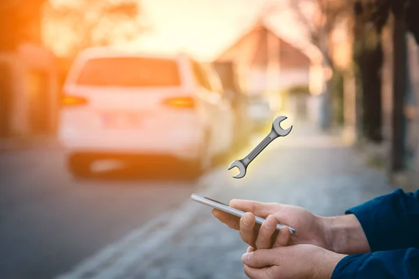 Search car service on smart phone. Smart car and new technologies in cars concept. Person with smart phone in hand sitting on the sidewalk and searching the nearest service.