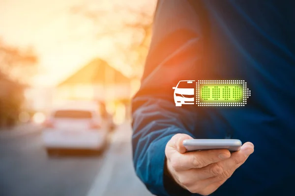 充电式电动车的概念 车主们正在用智能手机应用程序查看他的汽车的蓄电池状况 — 图库照片