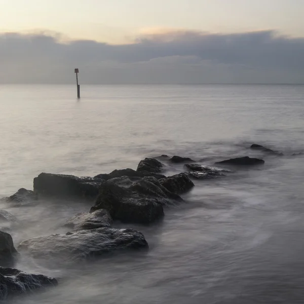 Stunning sunrise landscape over rocks in sea — Stock Photo, Image