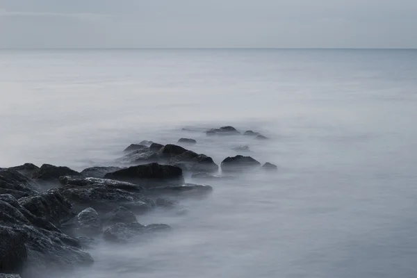 Prachtige zonsopgang landschap over rotsen in de zee — Stockfoto