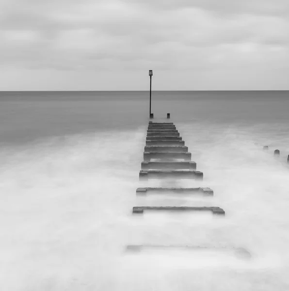 Svart och vit lång exponering liggande bild av havet och groynes — Stockfoto