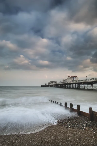 Beautiful long exposure sunset landscape image of pier at sea in