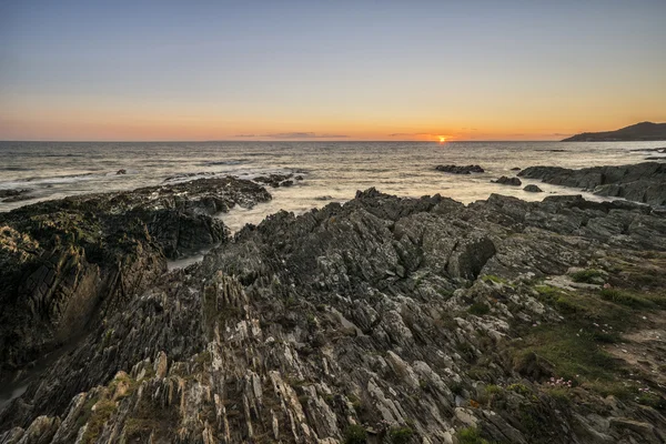 Beautiful vibrant sunset landscape image of calm sea against roc — Stock Photo, Image