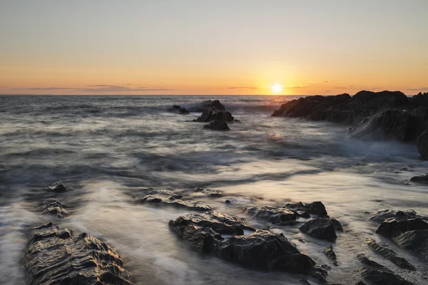 Hermoso paisaje de puesta de sol vibrante imagen de mar tranquilo contra roc — Foto de Stock