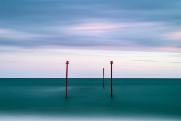 Stunning vibrant conceptual image of posts in sea standing senti — Stock Photo, Image