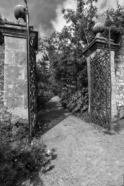 Puerta de jardín de hierro forjado viejo y pared de ladrillo en negro a — Foto de Stock