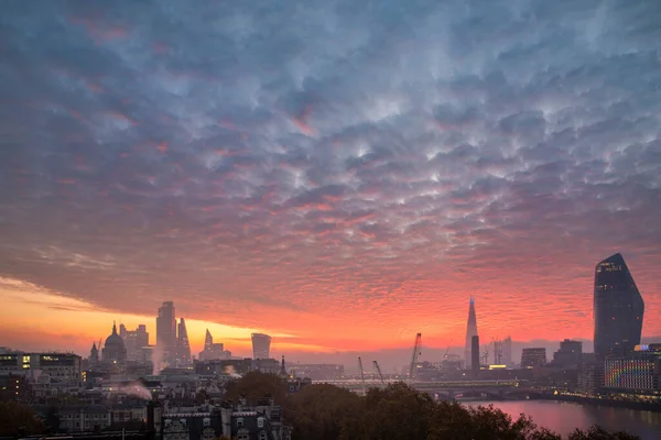 象徴的なランドマークの上に見事な空の形成を持つロンドンの都市スカイラインの壮大な日の出 — ストック写真
