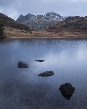 Lake District 'teki Blea Tarn' ın üzerinde kar kaplı Langdale Pikes 'le güzel bir kış gündoğumu.