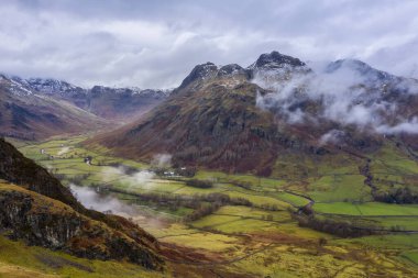 Langdale mızraklarının ve kışın alçak seviye bulutlar ve sisli vadisinin destansı uçan hava aracı görüntüsü.