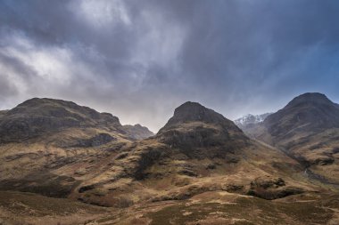 Islak bir kış gününde İskoçya 'nın Glencoe şehrindeki Üç Kız Kardeş' in destansı dramatik manzarası.