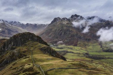 Langdale mızraklarının ve kışın alçak seviye bulutlar ve sisli vadisinin destansı uçan hava aracı görüntüsü.