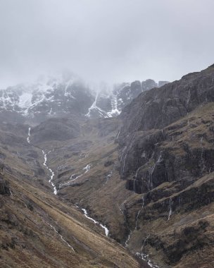 Islak bir kış gününde İskoçya 'nın Glencoe şehrindeki Üç Kız Kardeş' in destansı dramatik manzarası.