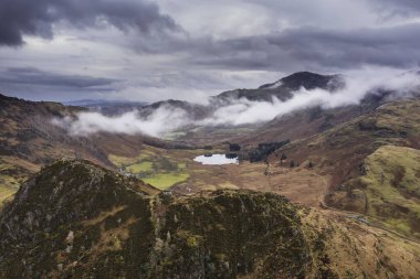 Langdale mızraklarının ve kışın alçak seviye bulutlar ve sisli vadisinin destansı uçan hava aracı görüntüsü.