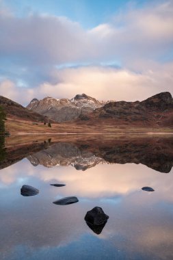 Lake District 'teki Blea Tarn' ın üzerinde kar kaplı Langdale Pikes 'le güzel bir kış gündoğumu.